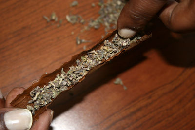 Close-up of hand making marijuana joint on table