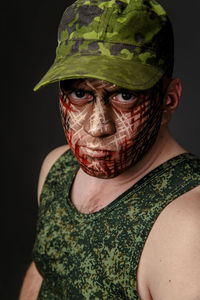 Portrait of soldier with camouflage make-up against black background