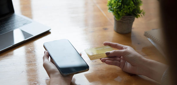 Midsection of woman using smart phone on table