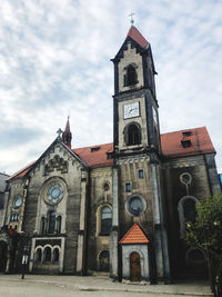 Low angle view of clock tower amidst buildings against sky