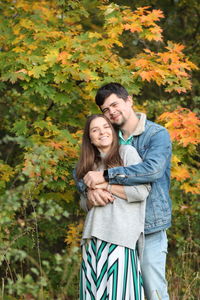 Smiling young woman standing against plants