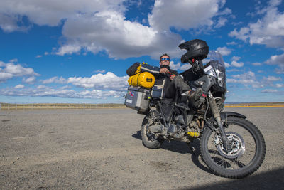 Man resting on his parked motorbike on a sunny day in patagonia, chile
