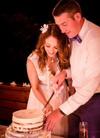 Close-up of couple cutting wedding cake