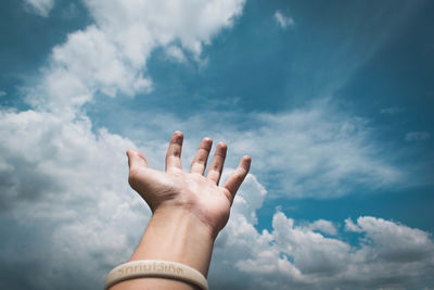 Low angle view of human hand against sky