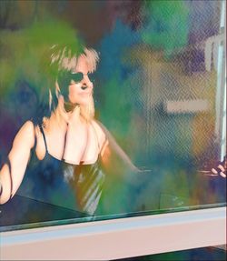 Portrait of woman wearing sunglasses at window