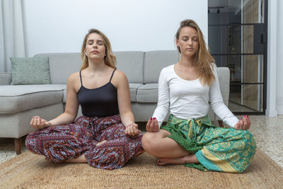 Couple of young women doing meditation at home person