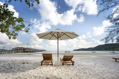 Deck chairs on beach against sky