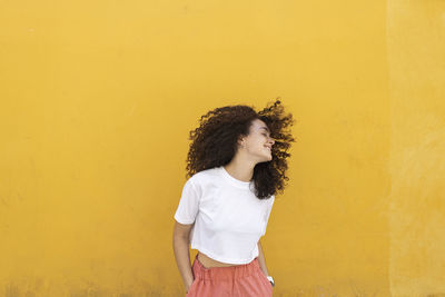 Woman tossing hair in front of yellow wall