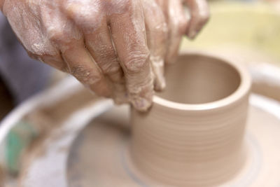 Cropped hands making pottery at workshop