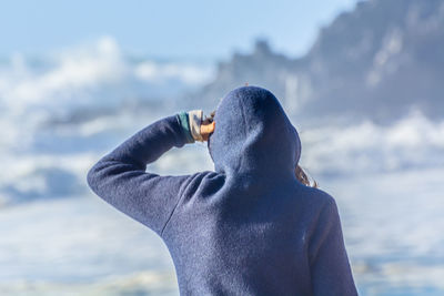 Rear view of man drinking water against sky