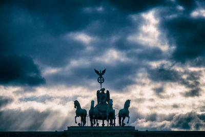 Low angle view of statue against storm clouds