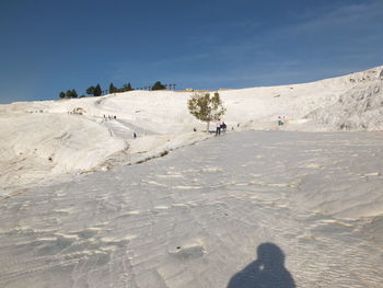 People on snow covered land against sky