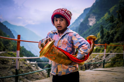 Portrait of young woman standing against mountain