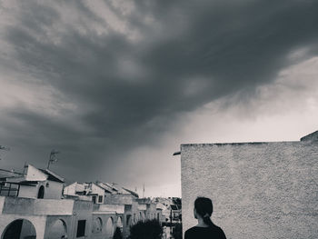 Man and buildings in city against sky