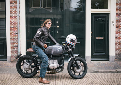 Young woman riding motorcycle on street against building