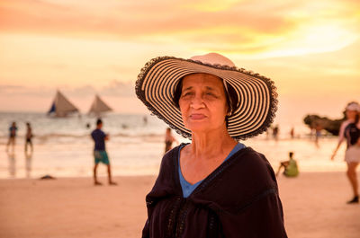 Portrait of woman on beach against sky during sunset