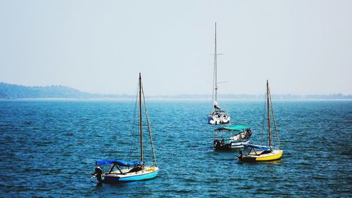 Sailboats moored in sea against clear sky