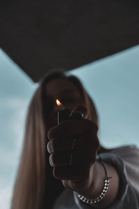 Portrait of woman holding cigarette lighter outdoors
