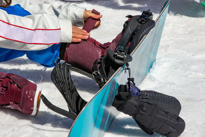 Low section of man wearing snowboard sitting on snow