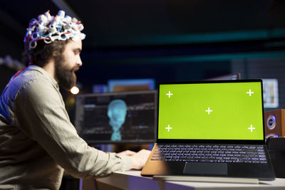Side view of man using laptop at home