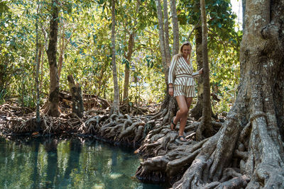 Man standing by tree trunk in forest