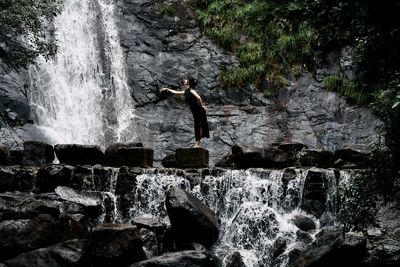 Rear view of man standing against waterfall