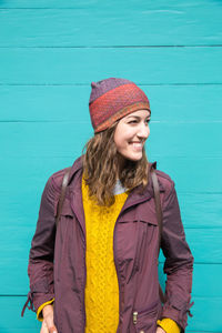 Smiling young woman standing against wall