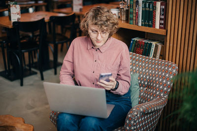 Young woman using digital tablet while sitting in cafe