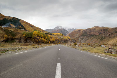 Road leading towards mountains against sky