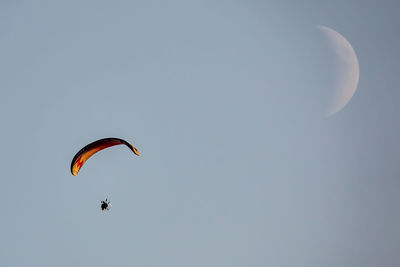 Low angle view of person paragliding against sky