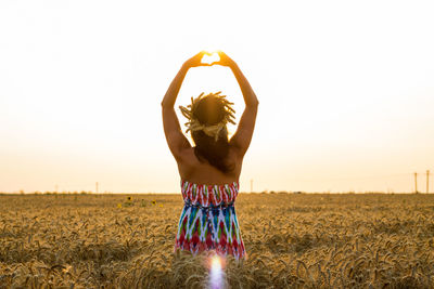 Young woman standing on field against clear sky