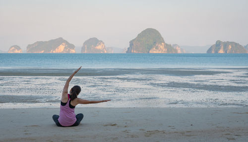 Young woman workout by doing yoga on the beach in the morning