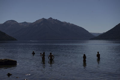 Group of people at beach against clear sky