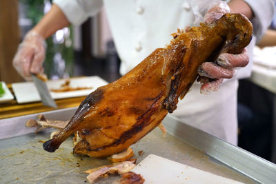 Midsection of chef preparing roasted meat at commercial kitchen