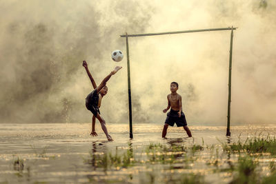 Boys playing soccer playing on rainy season