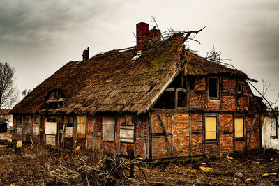 Old abandoned house on field against sky