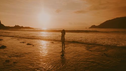 Silhouette man standing on beach against sky during sunset