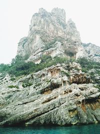 Rock formations in sea against clear sky