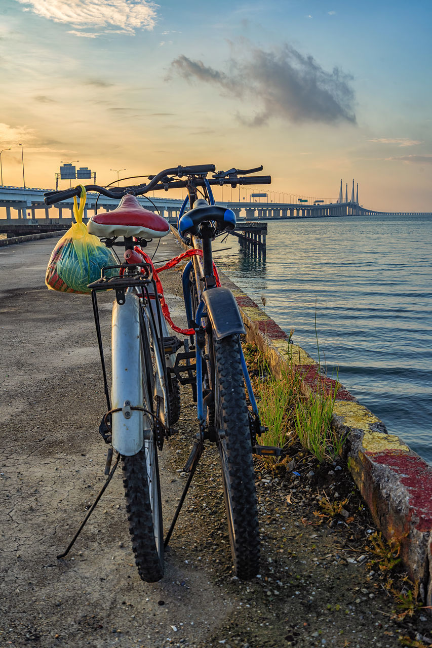 BICYCLE ON BEACH AGAINST SEA DURING SUNSET