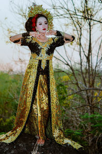 Portrait of woman standing by tree