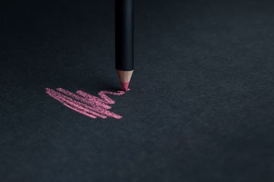 Scribble of pink pencil on black paper