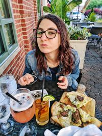 Portrait of young woman having pizza and cocktail at cafe