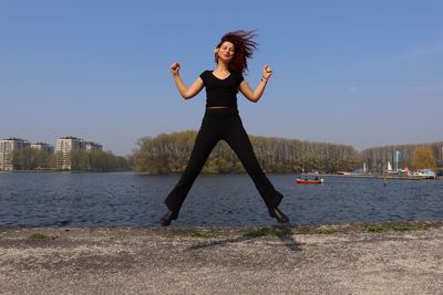 Woman standing by lake against sky