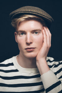 Portrait of teenage boy wearing hat against black background