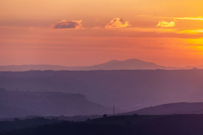 Scenic view of silhouette mountains against orange sky