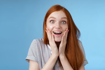 Portrait of a smiling young woman against blue background