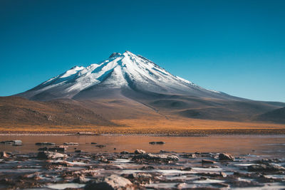 Scenic view of snowcapped mountains against clear blue sky