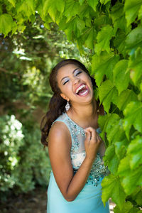 Cheerful young woman standing by plants in park