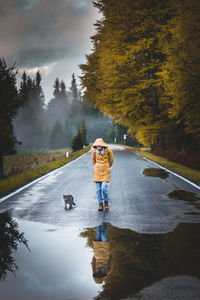 Man with dog on street amidst trees