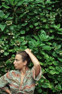 Young woman looking away while standing amidst leaves